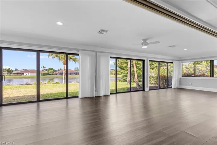 Spacious room featuring extensive sliding glass doors, contemporary wood-finish flooring, recessed lighting, and a ceiling fan
