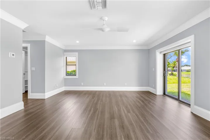 Spacious interior featuring wood-finish flooring, light gray walls, and white crown molding