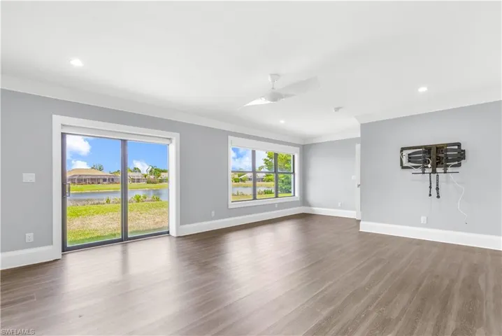 Spacious interior featuring wood-finish flooring, light gray walls, and white crown molding