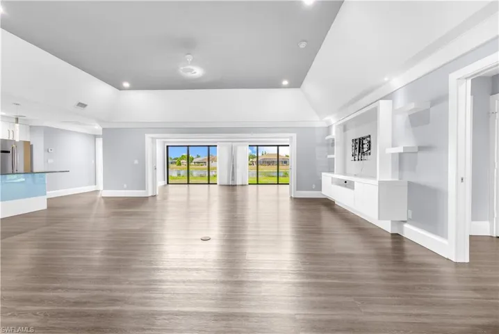 Expansive great room featuring wood-finish flooring, a vaulted ceiling with recessed lighting, and a built-in media center