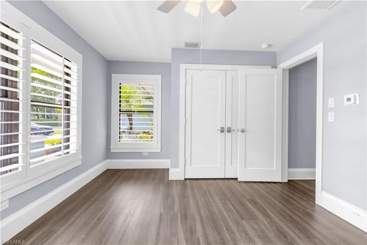 Room featuring wood-finish flooring, light blue walls, and white plantation shutters