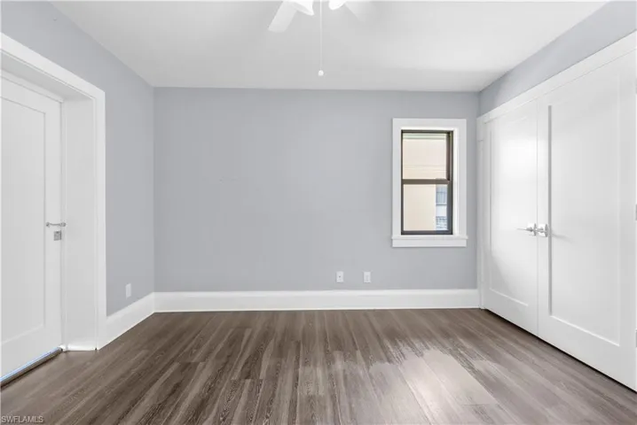 Spacious room featuring wood-finish flooring, light grey walls, and crisp white trim