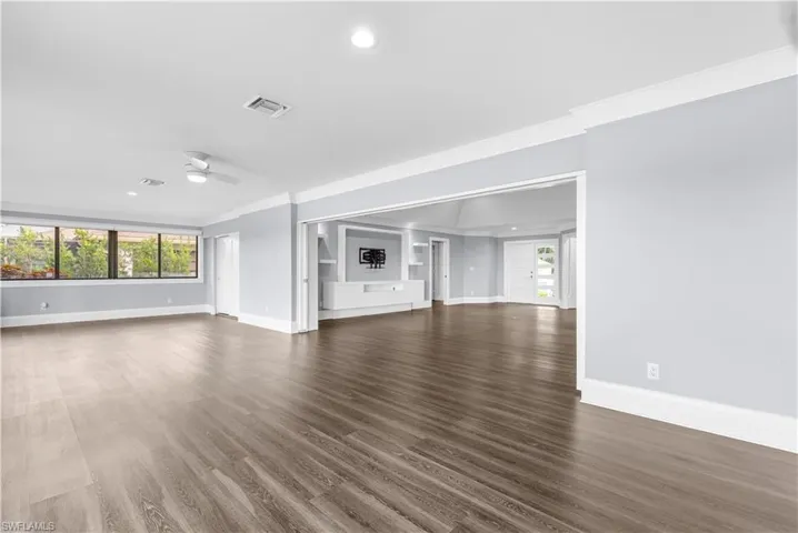 Spacious interior featuring wood-finish flooring, light gray walls, white crown molding, recessed lighting, and a ceiling fan