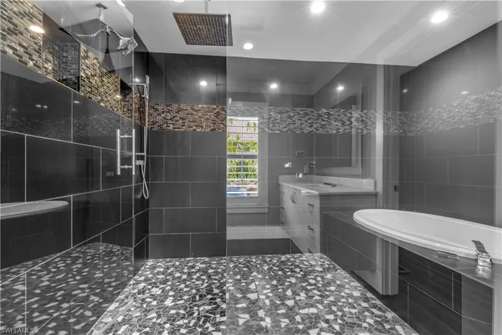 Spacious shower with mosaic tile flooring, dark large-format wall tiles, and a rainfall showerhead