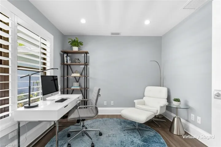 Interior room featuring light gray walls, wood-finish flooring, and white plantation shutters