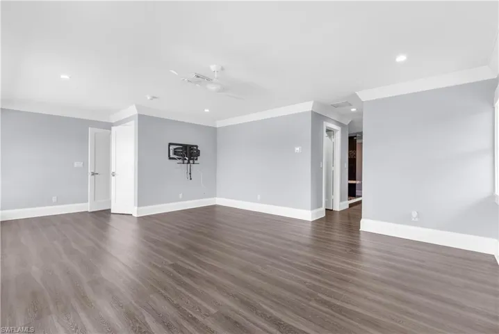 Spacious room featuring wood-finish flooring, light gray walls, white crown molding, and recessed lighting