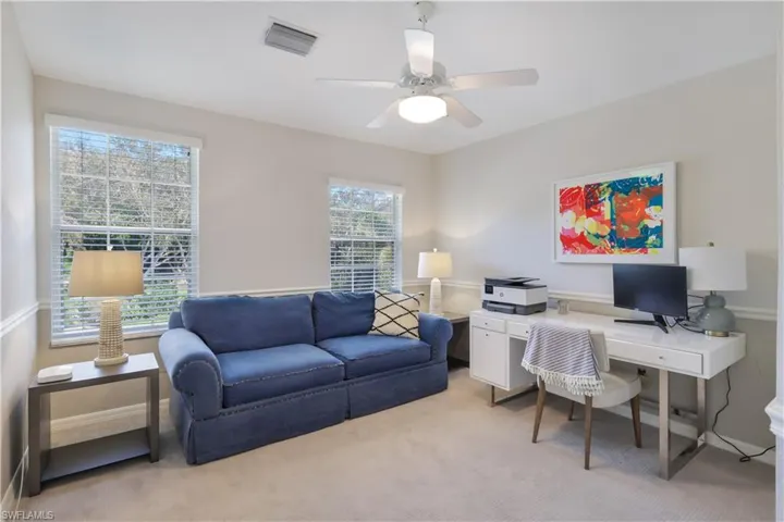 Carpeted bedroom/home office featuring ceiling fan