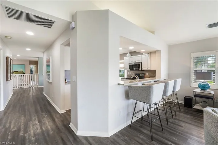 Kitchen featuring sink, kitchen peninsula, a kitchen breakfast bar, white cabinets, and dark hardwood / wood-style floors