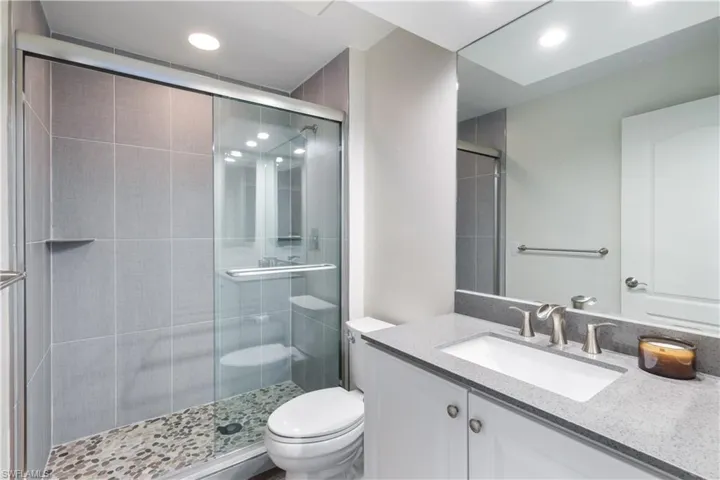 Bathroom featuring toilet, a shower with shower door, and vanity