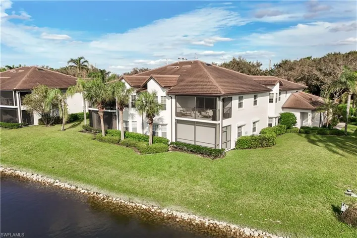 Rear view of house featuring a water view, a sunroom, and a lawn