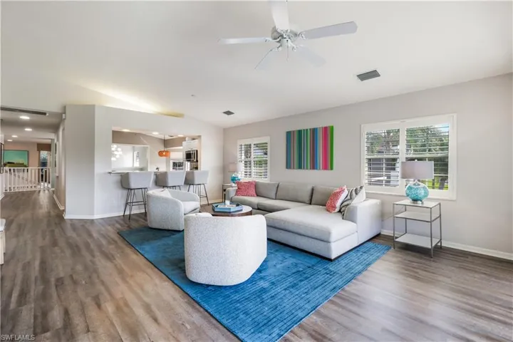 Living room featuring vaulted ceiling, wood-type flooring, and ceiling fan