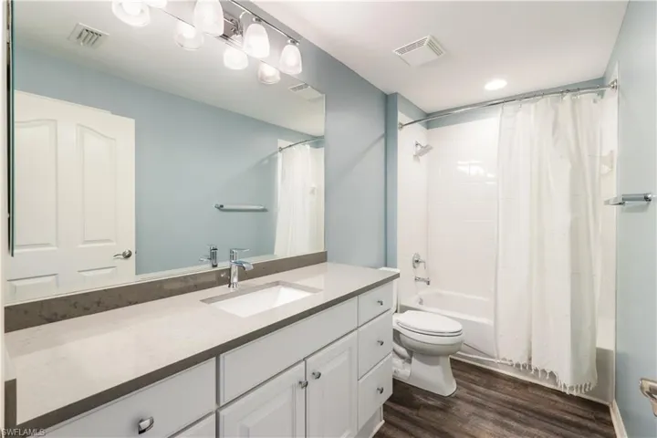 Full bathroom with vanity, toilet, hardwood / wood-style flooring, and shower / bath combo