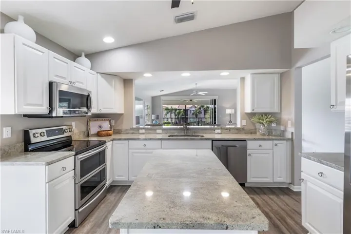 Kitchen featuring appliances with stainless steel finishes, lofted ceiling, and white cabinets