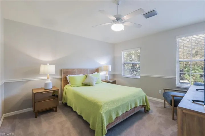 Carpeted bedroom with multiple windows and ceiling fan