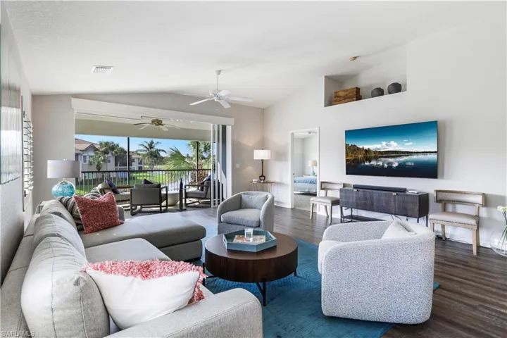 Living room featuring vaulted ceiling, ceiling fan, and dark hardwood / wood-style flooring