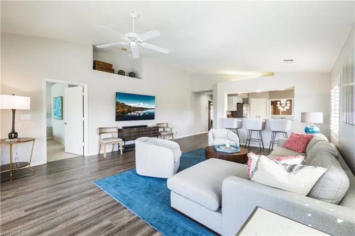 Living room featuring ceiling fan, vaulted ceiling, and dark hardwood / wood-style floors