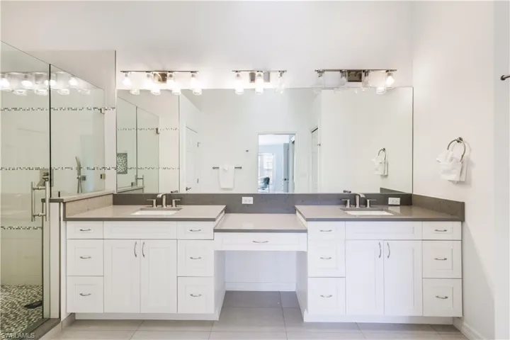 Bathroom featuring a shower with door, tile patterned flooring, and vanity