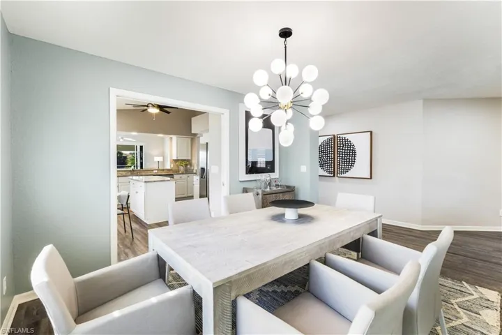 Dining space with wood-type flooring and ceiling fan with notable chandelier
