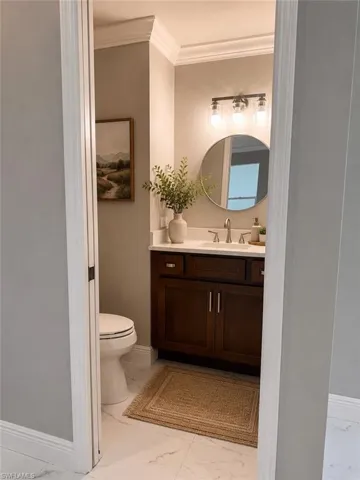 Powder room featuring a dark wood vanity with a white countertop and undermount sink, a circular mirror, and a three-light vanity fixture