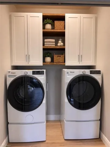 Laundry area featuring light wood-finish flooring, white baseboards, and light gray wall paint