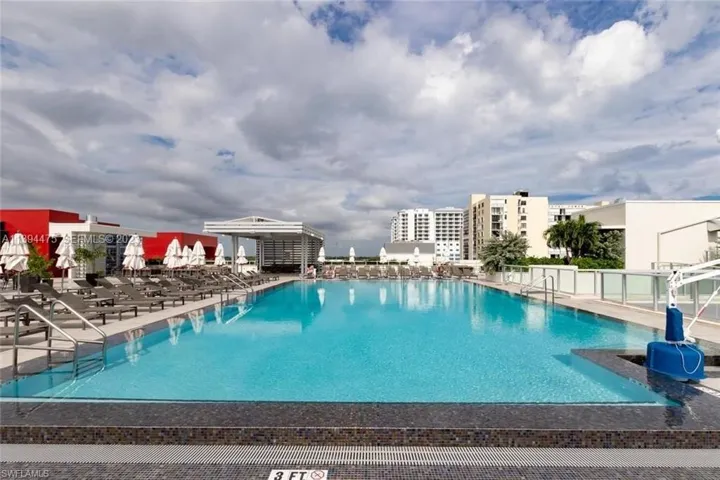 Expansive outdoor pool area featuring a large rectangular pool with a mosaic tile border