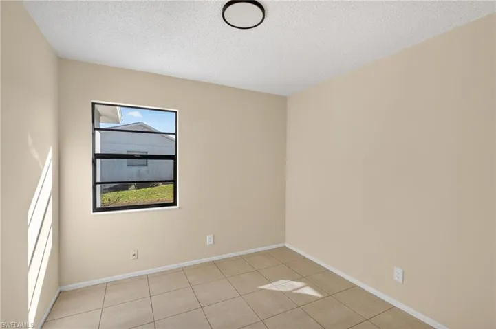 Empty room with a textured ceiling and light tile patterned floors