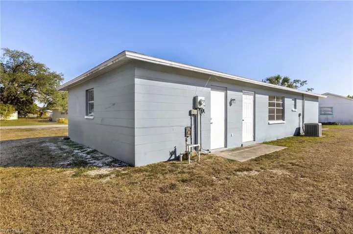 Back of property featuring a lawn and concrete block siding