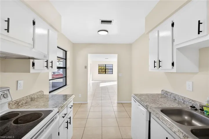 Kitchen with white appliances, white cabinets, light tile patterned floors, and light countertops