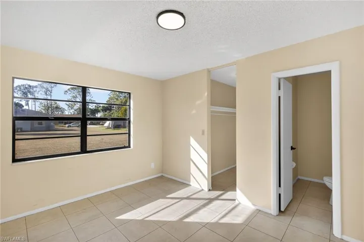 Empty room with a textured ceiling and light tile patterned floors