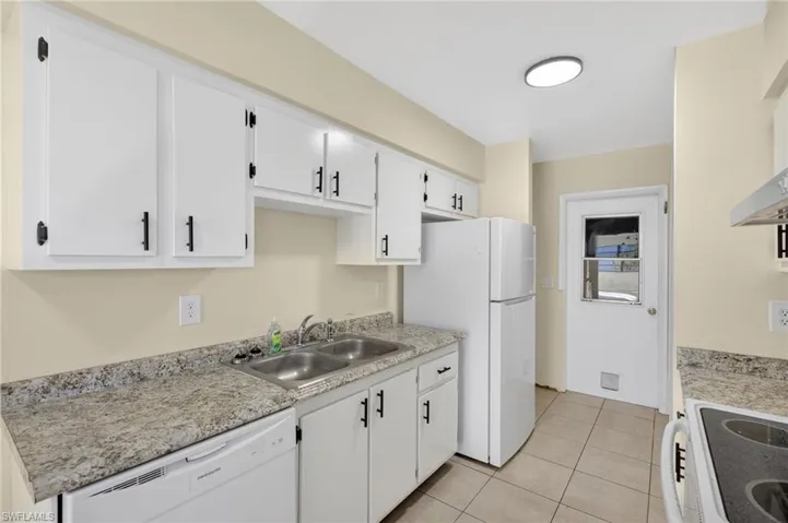 Kitchen with white appliances, light countertops, white cabinets, and light tile patterned flooring