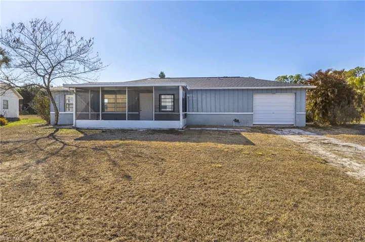 Single story home with a sunroom, an attached garage, a front lawn, a shingled roof, and driveway