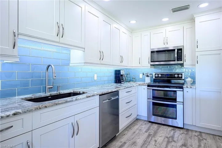 Kitchen featuring white cabinets, light wood-type flooring, sink, and appliances with stainless steel finishes
