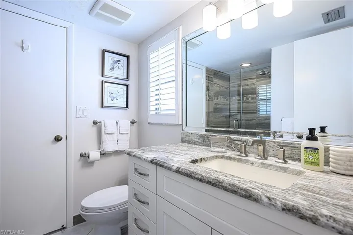 Bathroom with vanity, an enclosed shower, and toilet