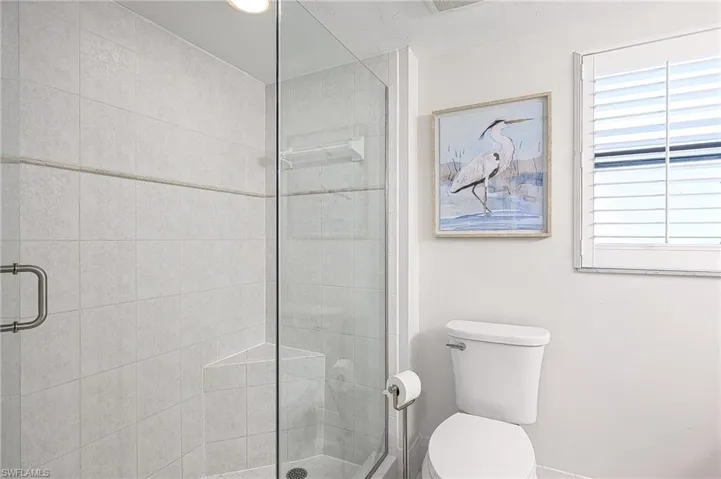 Bathroom featuring toilet and a shower with shower door