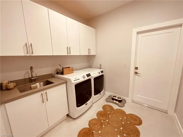 Washroom featuring cabinets, sink, and washer and dryer