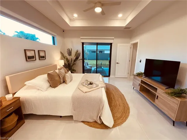 Bedroom featuring a raised ceiling, ceiling fan, and access to exterior
