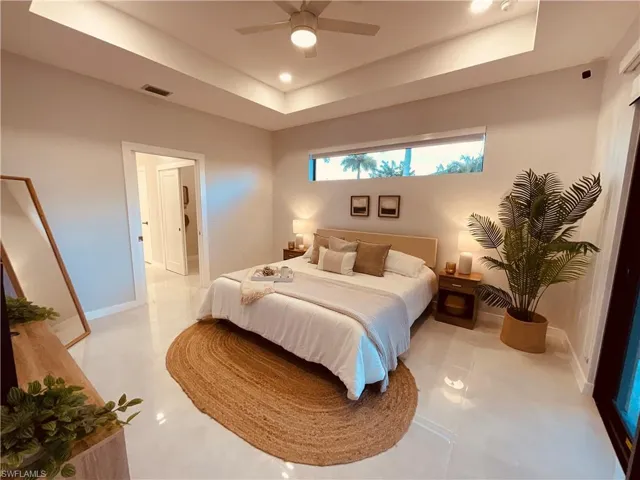 Bedroom featuring ceiling fan, light tile patterned flooring, and a tray ceiling