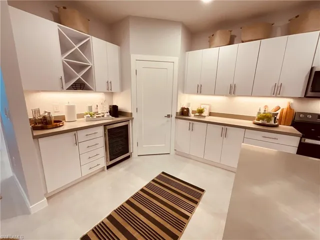 Kitchen with white cabinets, wine cooler, and range