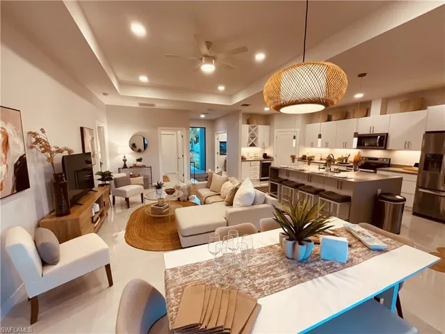 Living room with a raised ceiling, beverage cooler, ceiling fan, and sink
