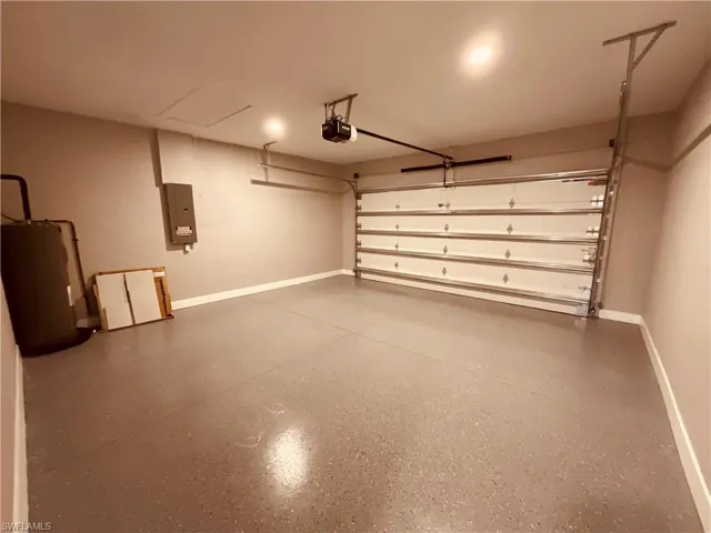 Garage with a garage door opener, water heater, and electric panel