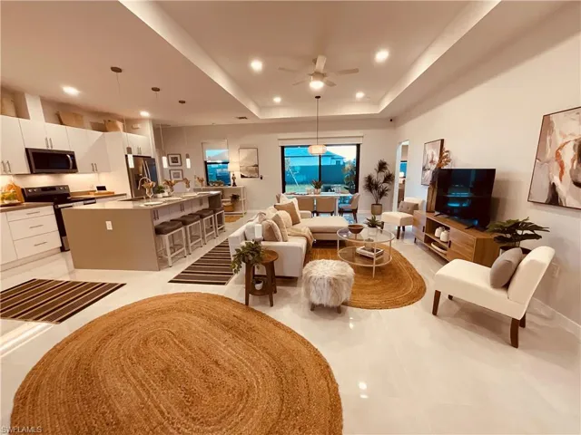 Living room featuring a tray ceiling, sink, and ceiling fan