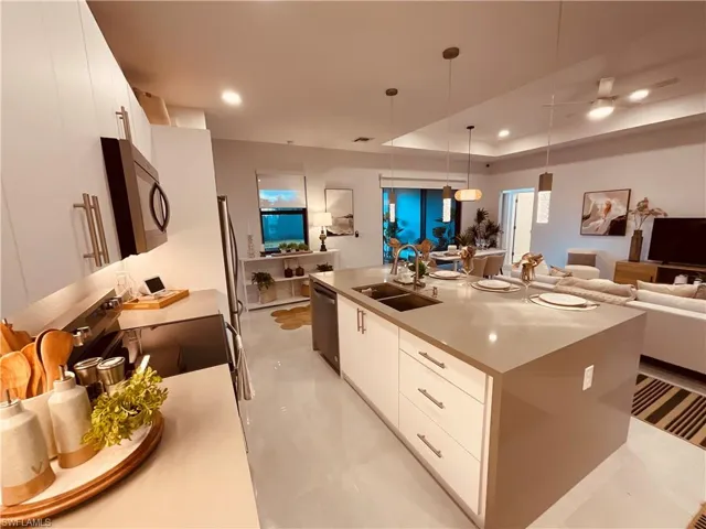 Kitchen featuring white cabinetry, a center island with sink, appliances with stainless steel finishes, and hanging light fixtures