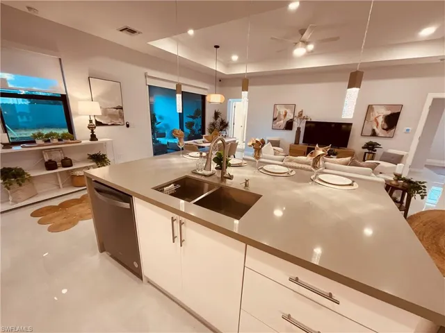 Kitchen featuring hanging light fixtures, white cabinetry, dishwasher, ceiling fan, and sink