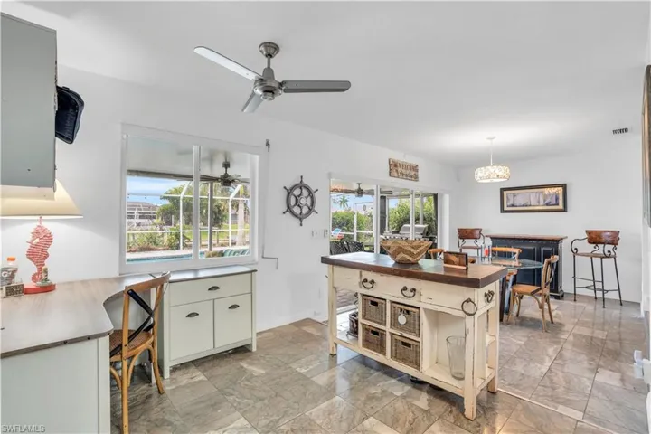 Kitchen with a wealth of natural light, visible vents, dark countertops, and ceiling fan with notable chandelier