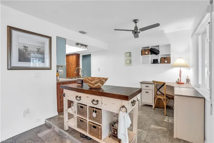 Office space with baseboards, visible vents, a ceiling fan, marble finish floor, and a sink
