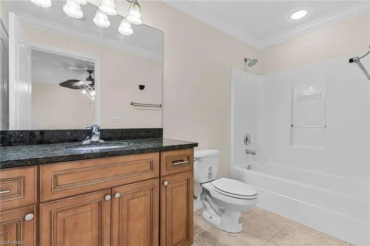 Full bathroom featuring ornamental molding,  shower combination, vanity, tile patterned floors, and toilet