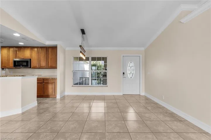 Kitchen with light tile patterned floors, pendant lighting, and ornamental molding