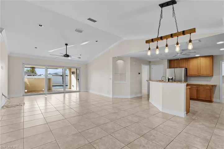 Kitchen featuring pendant lighting, stainless steel refrigerator with ice dispenser, light tile patterned flooring, and vaulted ceiling