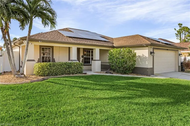 Ranch-style home with a garage, solar panels, and a front yard