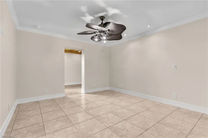 Spare room featuring ceiling fan, crown molding, and light tile patterned flooring